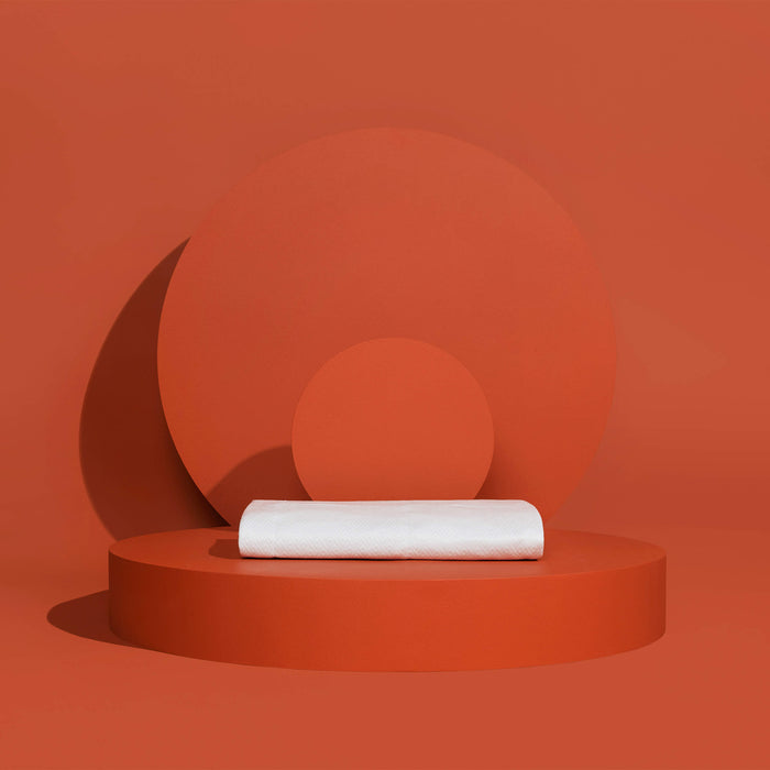 A folded Slumber Cloud Core Mattress Protector - Crib on a red background