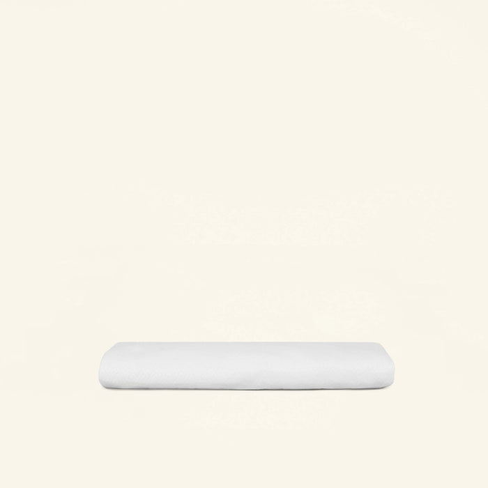 A folded Slumber Cloud Core Mattress Protector - Crib on a cream background