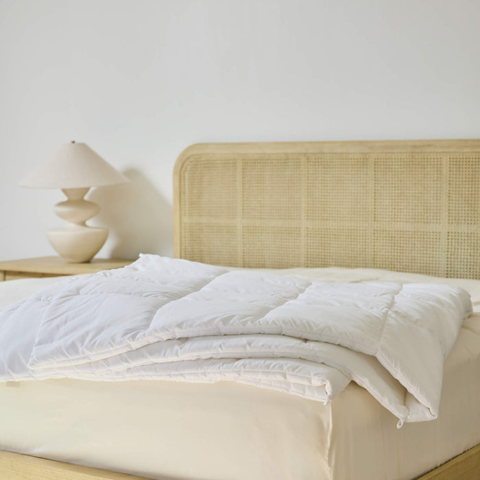 An Avec Goods Down Alternative Duvet Insert lying on the corner of a bed