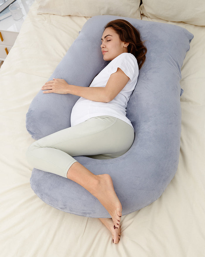 Pregnant woman resting on a gray U-shaped maternity pillow for comfortable sleep and body support.