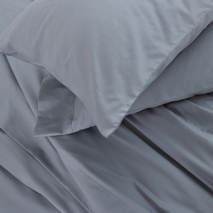 Overhead view of the Pewter Performance Cotton Sheets and pillowcases on the corner of a bed.