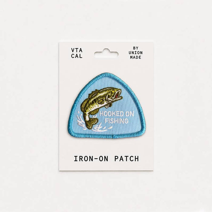 Forager Provisions LTD Hooked on Fishing embroidered iron-on patch featuring a bass fish on a blue triangular background.