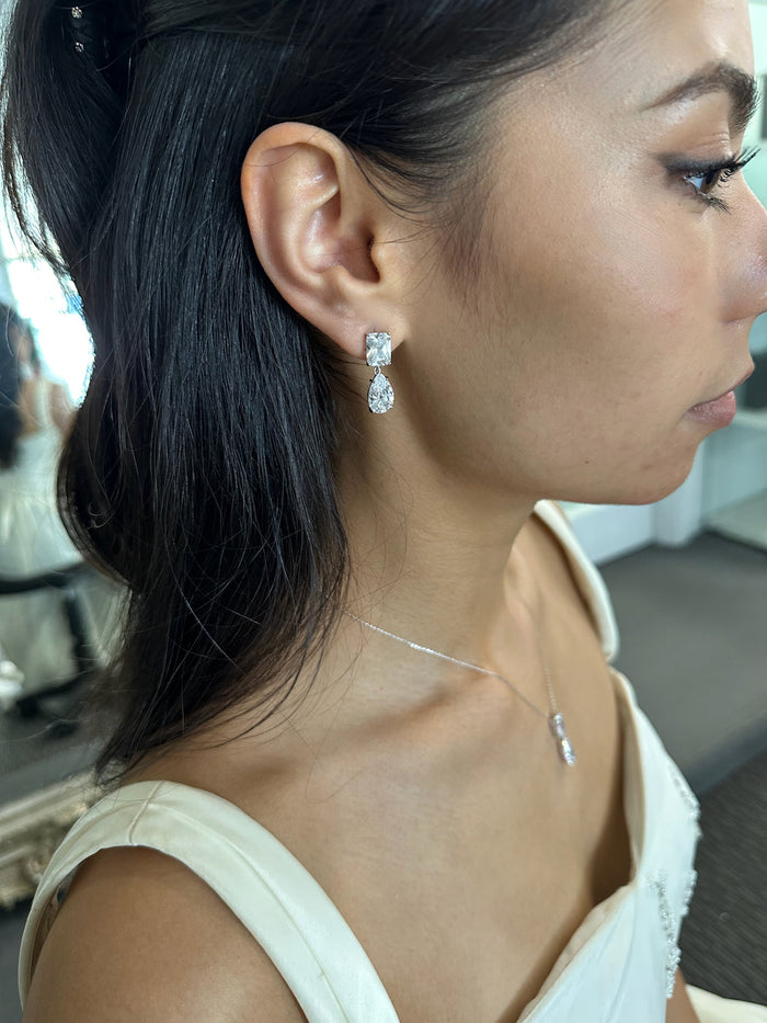 Close-up of a woman wearing silver earrings and a necklace.